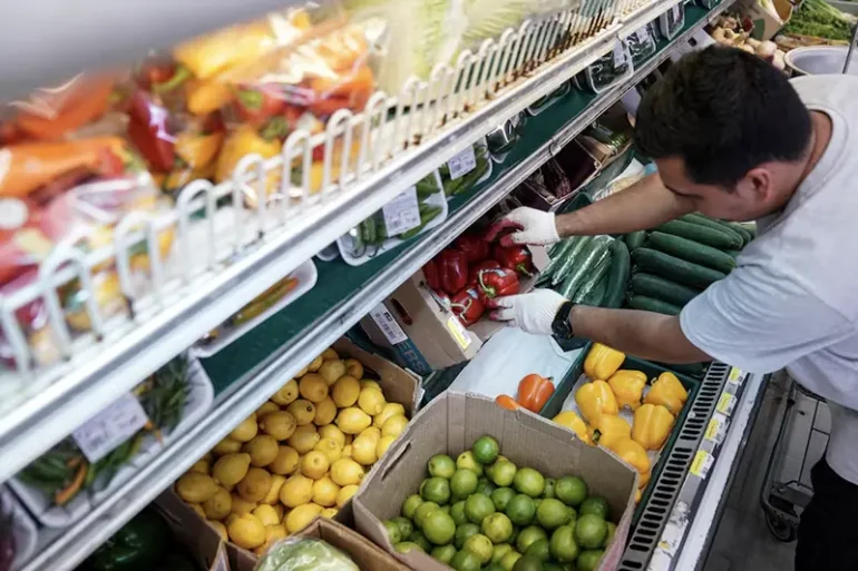 A man arranges produce at Best World Supermarket in the Mount Pleasant neighborhood of Washington, D.C., U.S., August 19, 2022. REUTERS/Sarah Silbiger/File Photo