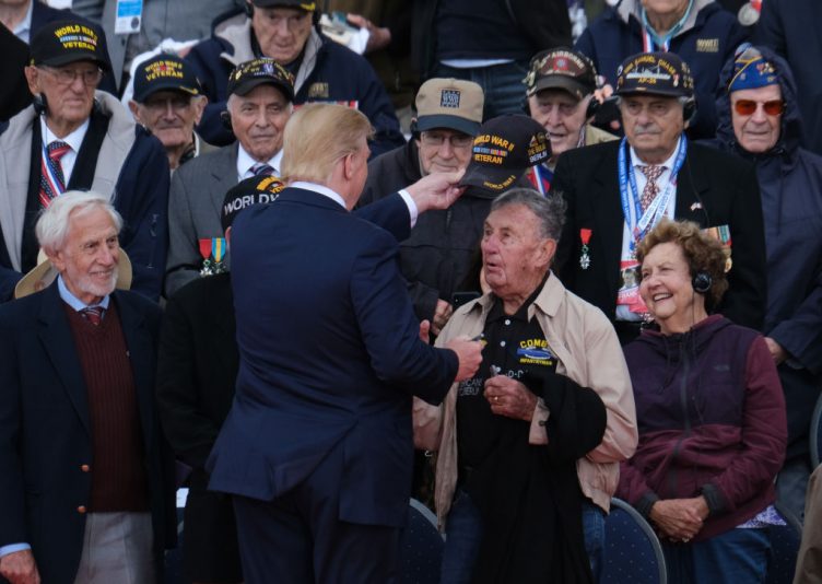 COLLEVILLE-SUR-MER, FRANCE - JUNE 06: U.S. President Donald Trump tips the cap of a U.S. veteran of the Battle of Normandy as other veterans look on during the main ceremony to mark the 75th anniversary of the World War II Allied D-Day invasion of Normandy at Normandy American Cemetery on June 06, 2019 near Colleville-Sur-Mer, France. Veterans, families, visitors, political leaders and military personnel are gathering in Normandy to commemorate D-Day, which heralded the Allied advance towards Germany and victory about 11 months later. (Photo by Sean Gallup/Getty Images)