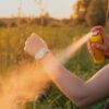 Close-up of young female backpacker tourist applying bug spray on hands