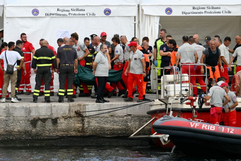 Rescuers carry a body bag in Porticello near Palermo, on August 21, 2024 two days after the British-flagged luxury yacht Bayesian sank. Divers searching for six missing people following the sinking of a superyacht off Sicily in a storm have found two bodies, a source close to the search told AFP. The Bayesian, which had 22 people aboard including 10 crew, was anchored some 700 metres from port before dawn when it was struck by a waterspout, a sort of mini tornado. Fifteen people aboard, including a mother with a one-year-old baby, were plucked to safety; one man has been found dead; and six people remain missing. (Photo by Alberto PIZZOLI / AFP) (Photo by ALBERTO PIZZOLI/AFP via Getty Images)