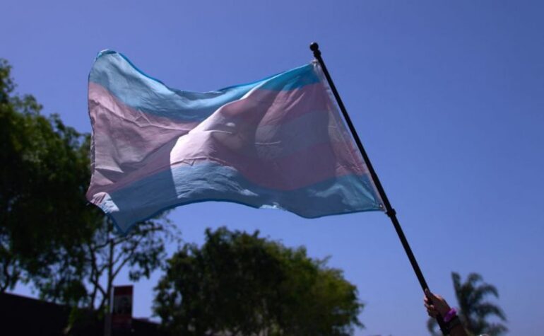 A Transgender Pride Flag is held above the crowd of LGBTQ+ activists during the Los Angeles LGBT Center's "Drag March LA: The March on Santa Monica Boulevard", in West Hollywood, California, on Easter Sunday April 9, 2023. The march comes in response to more than 400 pieces of legislation targeting the LGBTQ+ community that government officials across the United States have proposed or passed in 2023. (Photo by ALLISON DINNER / AFP) (Photo by ALLISON DINNER/AFP via Getty Images)