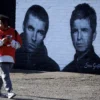 A man walks past a mural of Oasis band members Liam and Noel Gallagher by artist Snow Graffiti on the wall of the Coach and Horses pub in Whitefield, near Manchester, Britain, August 31, 2024. REUTERS/Phil Noble/File Photo