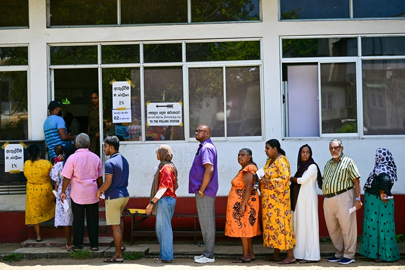 People wait in a queue to cast their ballots at a polling station during voting in Sri Lanka's presidential election in Colombo on September 21, 2024. Cash-strapped Sri Lanka began voting for its next president September 21 in an effective referendum on an unpopular International Monetary Fund austerity plan enacted after the island nation's unprecedented financial crisis. (Photo by Ishara S.KODIKARA / AFP) (Photo by ISHARA S.KODIKARA/AFP via Getty Images)