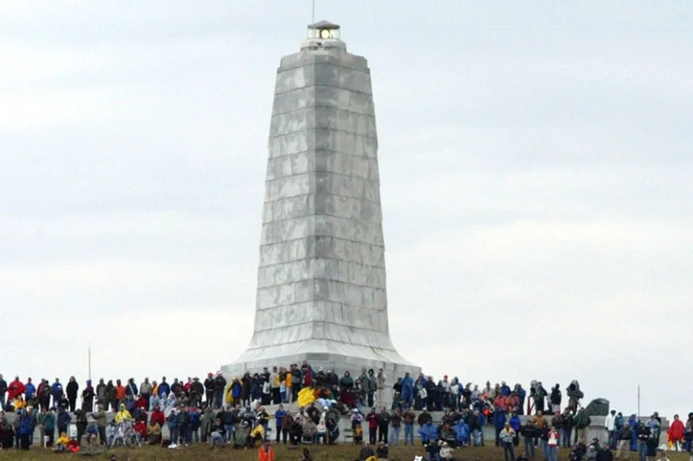 Spectators wait to see a second attempt at flying a replica of the 1903 Wright Flyer after an unsuccessful first attempt marking the Wright brother's historic first flight during Centennial celebrations at the Wright Brothers National Memorial December 17, 2003 in Kill Devil Hills, North Carolina. The reenactment marked the finale of the six-day celebration. (Photo by Corey Lowenstein-Pool/Getty Images)