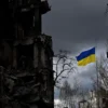 TOPSHOT - The Ukrainian flag flutters between buildings destroyed in bombardment, in the Ukrainian town of Borodianka, in the Kyiv region on April 17, 2022. - Russia invaded Ukraine on February 24, 2022. (Photo by Sergei SUPINSKY / AFP) (Photo by SERGEI SUPINSKY/AFP via Getty Images)