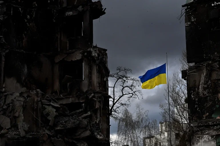 TOPSHOT - The Ukrainian flag flutters between buildings destroyed in bombardment, in the Ukrainian town of Borodianka, in the Kyiv region on April 17, 2022. - Russia invaded Ukraine on February 24, 2022. (Photo by Sergei SUPINSKY / AFP) (Photo by SERGEI SUPINSKY/AFP via Getty Images)