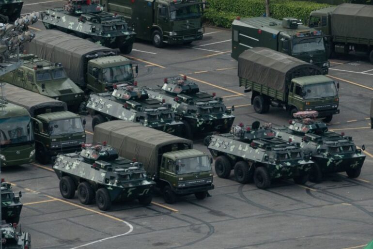 TOPSHOT - Trucks and armoured personnel carriers are seen parked at the Shenzhen Bay stadium in Shenzhen, bordering Hong Kong in China's southern Guangdong province, on August 16, 2019. - Chinese military personnel and armoured personnel carriers have mustered in large numbers across the border in Shenzhen, as Hong Kong's pro-democracy movement faces a major test this weekend as it tries to muster another huge crowd following criticism over a recent violent airport protest and as Beijing ramps up its bellicose threats. (Photo by STR / AFP) (Photo credit should read STR/AFP via Getty Images)