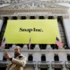 A man takes a photograph of the front of the New York Stock Exchange (NYSE) with a Snap Inc. logo hung on the front of it in New York, U.S., March 2, 2017. REUTERS/Lucas Jackson/File Photo