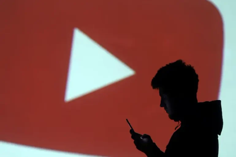 A silhouette of a mobile user is seen next to a screen projection of Youtube logo in this picture illustration taken March 28, 2018. REUTERS/Dado Ruvic/Illustration/ File Photo