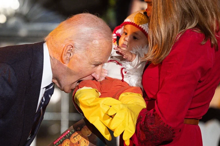 TOPSHOT - US President Joe Biden jokingly bites a baby dressed as a chicken as he hosts a Halloween trick-or-treat event at the South Portico of the White House in Washington, DC, on October 30, 2024. (Photo by Tierney CROSS / AFP) (Photo by TIERNEY CROSS/AFP via Getty Images)