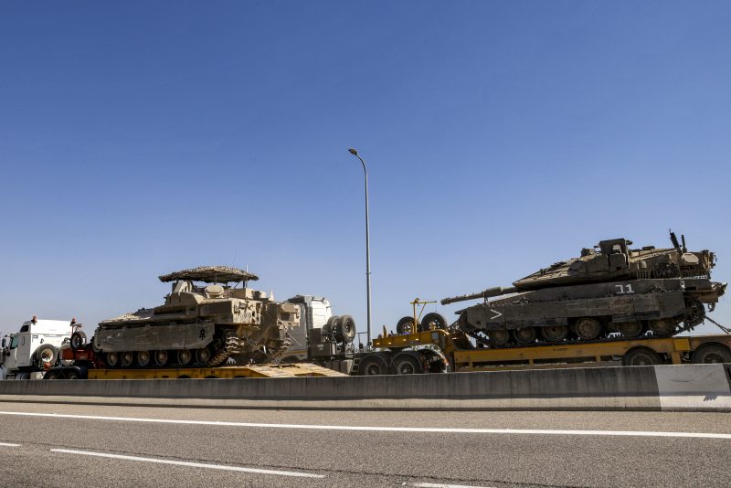 Trucks transport an Israeli army main battle tank and an infantry-fighting vehicle (IFV) headed for deployment along the border with Lebanon, along a highway in northern Israel on September 28, 2024. (Photo by Jalaa MAREY / AFP) (Photo by JALAA MAREY/AFP via Getty Images)