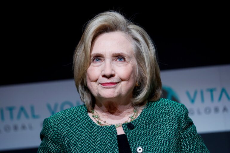 Hillary Clinton delivering a speech at the Vital Voices Global Festival in Washington, DC, wearing a green jacket