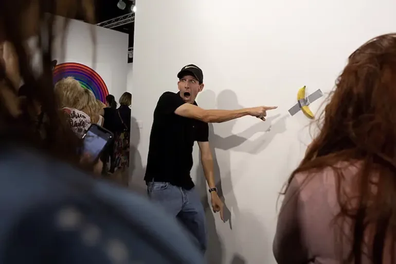 A man poses for a photo next to a banana attached with duct-tape that replaces the artwork 'Comedian' by the artist Maurizio Cattelan, which was eaten by David Datuna, in Miami Beach, Florida, December 7, 2019. REUTERS/Eva Marie Uzcategui/File Photo