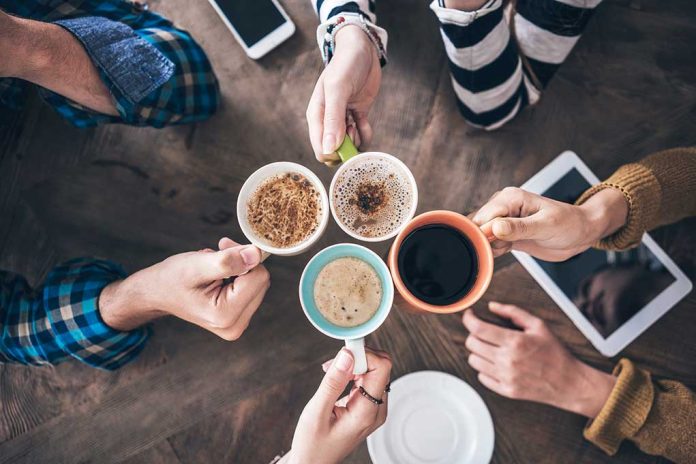 Hands holding different mugs over table.