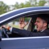 Man yelling inside a car, looking frustrated