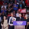 The family of Nicholas Douglas Quets speaks while former US President and Republican presidential candidate Donald Trump (3rd L) holds a photo of him, during a campaign rally at Lee's Family Forum in Henderson, Nevada, October 31, 2024. Quets, a retired US Marine from Tucson, Arizona, was shot and killed in Northern Mexico on October 19. (Photo by Ian Maule / AFP) (Photo by IAN MAULE/AFP via Getty Images)