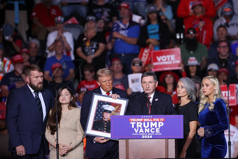 The family of Nicholas Douglas Quets speaks while former US President and Republican presidential candidate Donald Trump (3rd L) holds a photo of him, during a campaign rally at Lee's Family Forum in Henderson, Nevada, October 31, 2024. Quets, a retired US Marine from Tucson, Arizona, was shot and killed in Northern Mexico on October 19. (Photo by Ian Maule / AFP) (Photo by IAN MAULE/AFP via Getty Images)