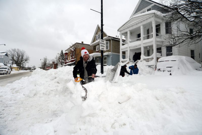 BUFFALO, NY - DECEMBER 27: Luke Bennett helps to clear heavy snow for his neighbors along South Park Avenue on December 27, 2022 in Buffalo, New York. The historic winter storm Elliott dumped up to four feet of snow, leaving thousands without power and at least 28 confirmed dead in the city of Buffalo and the surrounding suburbs. (Photo by John Normile/Getty Images)