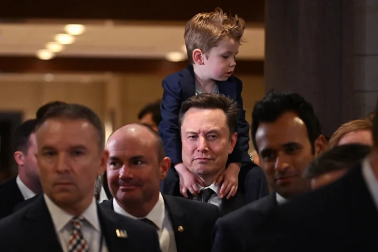 TOPSHOT - Tesla CEO Elon Musk (C), co-chair of the newly created Department of Government Efficiency (DOGE), carries his son "X" on his shoulders before a meeting with members of Congress at the US Capitol in Washington, DC, on December 5, 2024. President-elect Trump rewarded the Tesla, X and SpaceX chief for his support in the White House race by naming him head of the newly created Department of Government Efficiency, along with another wealthy ally, Vivek Ramaswamy. (Photo by ROBERTO SCHMIDT / AFP) (Photo by ROBERTO SCHMIDT/AFP via Getty Images)