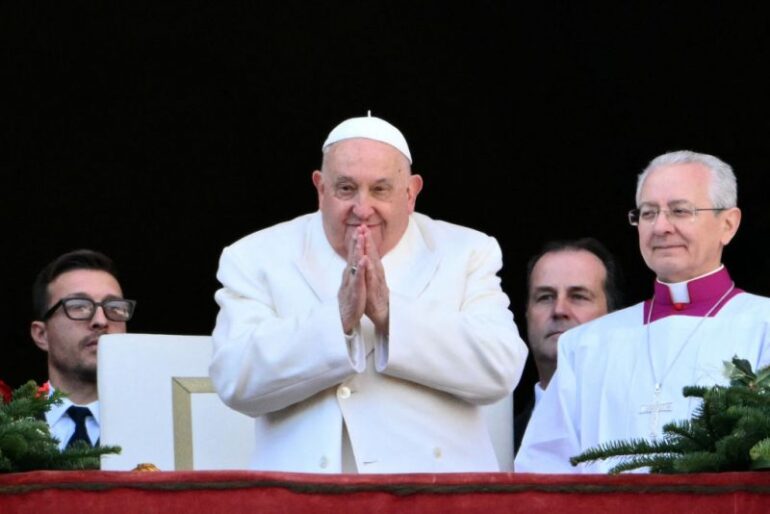 TOPSHOT - Pope Francis greets the crowd from the main balcony of St. Peter's basilica after the Urbi et Orbi message and blessing to the city and the world as part of Christmas celebrations, at St Peter's square in the Vatican on December 25, 2024. (Photo by Alberto PIZZOLI / AFP) (Photo by ALBERTO PIZZOLI/AFP via Getty Images)