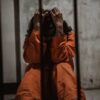 Person sitting in jail cell wearing orange jumpsuit