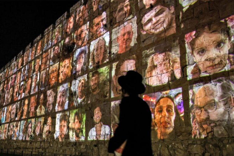 TOPSHOT - An Ultra-Orthodox Jewish man walks outside the walls of the old city of Jerusalem, on which are projected pictures of the hostages abducted by Palestinian militants on the October 7 attack and currently held in the Gaza Strip, on November 6, 2023, amid the ongoing battles between Israel and the militant group Hamas. (Photo by AHMAD GHARABLI / AFP) (Photo by AHMAD GHARABLI/AFP via Getty Images)