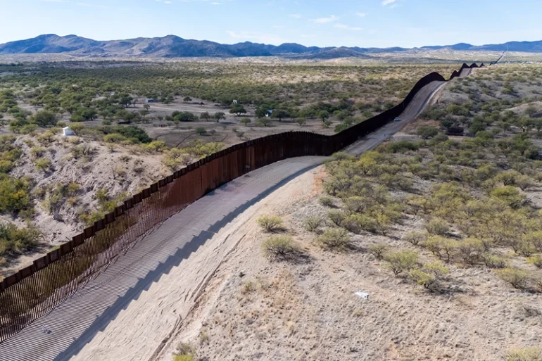 TOPSHOT - This aerial picture taken on December 8, 2023 shows the US-Mexico border wall in Sasabe, Arizona. Jaguars don't understand borders, but where the United States meets Mexico, they are having to adapt to them. Once the master of the plains of the Sonoran Desert, the animal is now struggling to survive in a landscape cut in two by a wall The barrier, which former US President Donald Trump boasted he would make "impenetrable" does little to discourage the thousands of people from Latin America, Asia, Africa and Eastern Europe who arrive every day. But, say conservationists, it is deadly to wildlife. (Photo by VALERIE MACON / AFP) (Photo by VALERIE MACON/AFP via Getty Images)