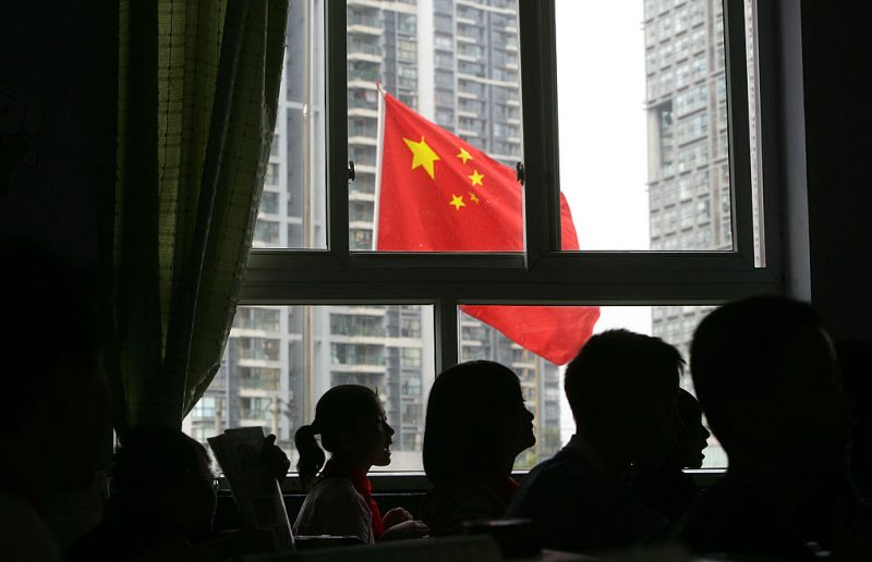 CHENGDU, CHINA - MAY 19: (CHINA OUT) Students look at a Chinese national flag flying at half-mast from a school classroom as China begins three days of national mourning for victim of the earthquake on May 19, 2008 in Chengdu, Sichuan province, China. The period of mourning will include a three minute silence which will be observed exactly one week after the earthquake hit. A major earthquake measuring 8.0 on the Richter scale, the worst in 58 years, jolted China's Sichuan Province May 12. The death toll is now estimated at over 32,000 people and is expected to rise, as 100,000 military troops continue rescue operations. (Photo by China Photos/Getty Images)