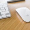 A Magic Mouse on a desk next to a Magic Keyboard.