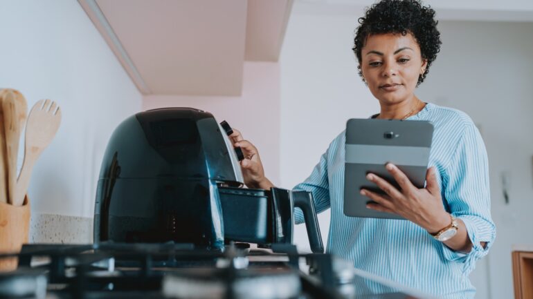 Woman setting up air fryer using tablet