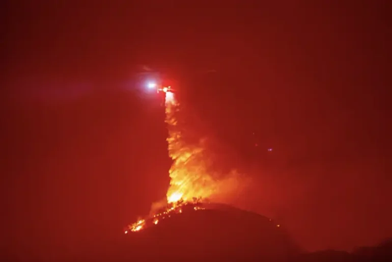 A helicopter drops water as the Hughes Fire burns near Castaic Lake, north of Santa Clarita, California, U.S. January 22, 2025. REUTERS/Ringo Chiu/File Photo