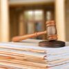 Gavel resting on stack of paperwork in courtroom