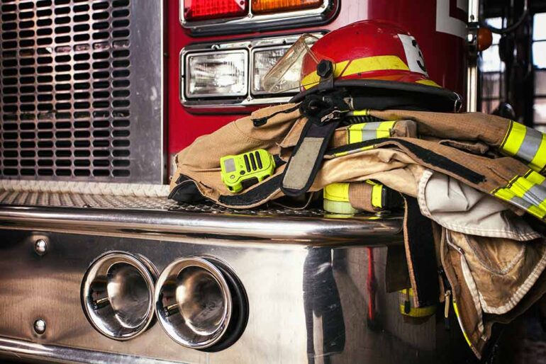 Firefighter gear on a fire truck bumper.