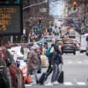 Pedestrians walk past a congestion pricing warning sign on 5th Avenue as congestion pricing begins taking effect in New York City on January 05, 2024. On Sunday New York is reviving a controversial scheme to charge drivers entering parts of the city, a first in the United States, putting local authorities on a collision course with President-elect Donald Trump. (Photo by KENA BETANCUR / AFP) (Photo by KENA BETANCUR/AFP via Getty Images)