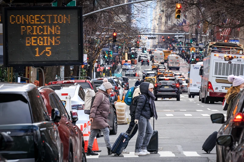 Pedestrians walk past a congestion pricing warning sign on 5th Avenue as congestion pricing begins taking effect in New York City on January 05, 2024. On Sunday New York is reviving a controversial scheme to charge drivers entering parts of the city, a first in the United States, putting local authorities on a collision course with President-elect Donald Trump. (Photo by KENA BETANCUR / AFP) (Photo by KENA BETANCUR/AFP via Getty Images)