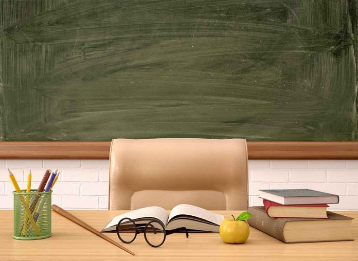 Classroom desk with books, apple, and chalkboard