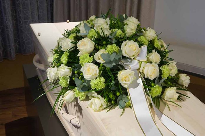 White roses on a coffin with ribbon.