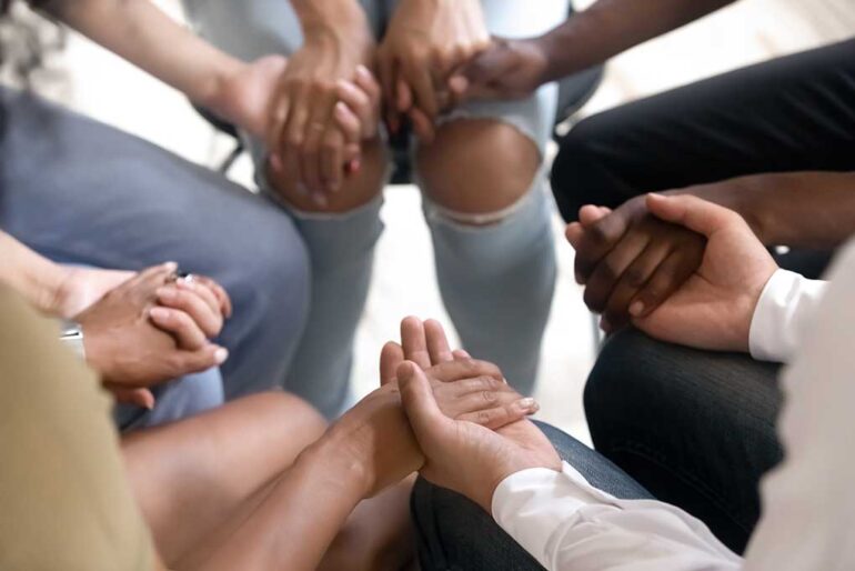 Group of diverse people holding hands in a circle.