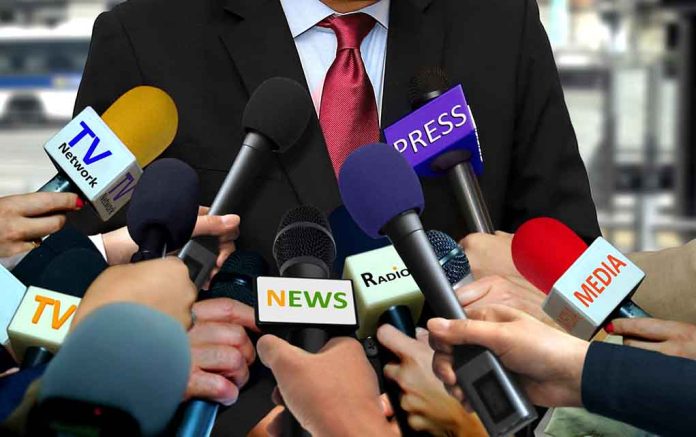 Person surrounded by microphones from various media