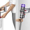 Dyson Digital Slim cordless vacuum having its dust cup emptied (left) and being docked on a wall (right)