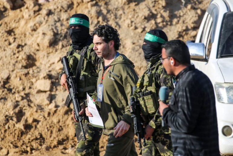 TOPSHOT - Palestinian militant group Hamas fighters escort Israeli-French hostage Ofer Kalderon before handing him over to a Red Cross team in Khan Yunis on February 1, 2025, as part of fourth hostage-prisoner exchange. (Photo by Eyad BABA / AFP) (Photo by EYAD BABA/AFP via Getty Images)