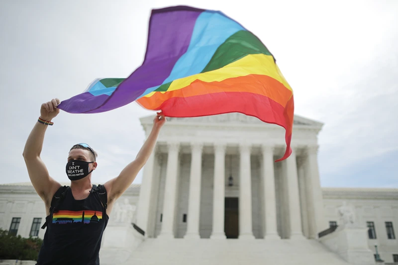 WASHINGTON, DC - JUNE 15: Joseph Fons holding a Pride Flag in front of the U.S. Supreme Court building after the court ruled that LGBTQ people can not be disciplined or fired based on their sexual orientation, Washington, DC, June 15, 2020. With Chief Justice John Roberts and Justice Neil Gorsuch joining the Democratic appointees, the court ruled 6-3 that the Civil Rights Act of 1964 bans bias based on sexual orientation or gender identity. Fons is wearing a Black Lives Matter mask with the words 'I Can't Breathe', as a precaution against Covid-19. (Photo by Chip Somodevilla/Getty Images)