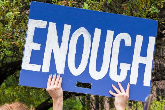 Hands holding blue sign saying enough