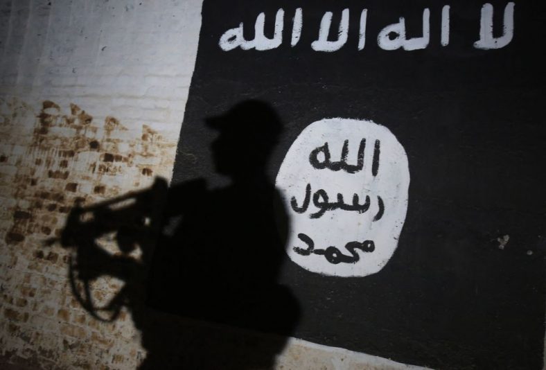 TOPSHOT - A member of the Iraqi forces walks past a mural bearing the logo of the Islamic State (IS) group in a tunnel that was reportedly used as a training centre by the jihadists, on March 1, 2017, in the village of Albu Sayf, on the southern outskirts of Mosul. Iraqi forces launched a major push on February 19 to recapture the west of Mosul from the Islamic State jihadist group, retaking the airport and then advancing north. (Photo by AHMAD AL-RUBAYE / AFP) (Photo by AHMAD AL-RUBAYE/AFP via Getty Images)