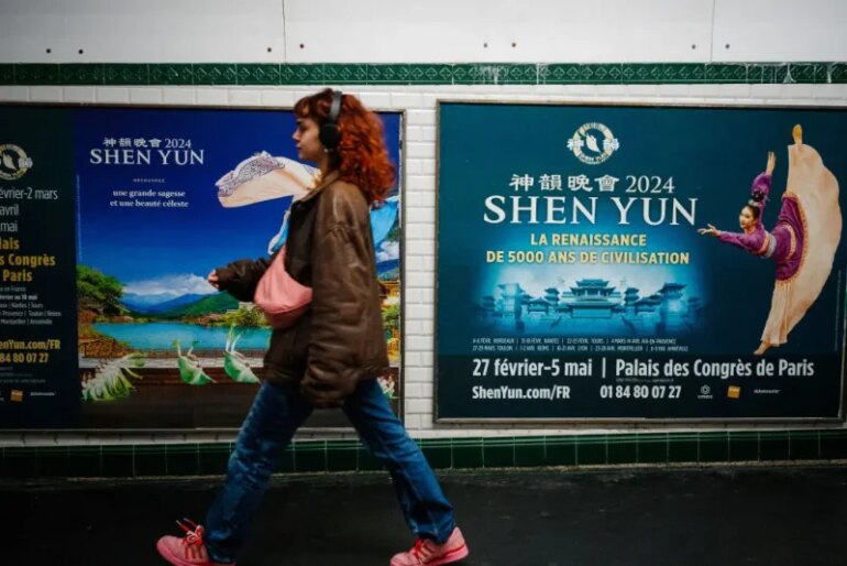 This photograph taken on March 1, 2024, shows a woman walking past posters of the Shen Yun dance show in a metro station in Paris. Dancers dressed in colourful costumes gracefully twirl in front of digitised landscapes of China, with an ambiguous message in the background: since 2006, the Chinese-American company Shen Yun, currently on tour in France, has used its grandiose shows to spread vehement criticism of Beijing and conservative rhetoric around the world. (Photo by Dimitar DILKOFF / AFP) (Photo by DIMITAR DILKOFF/AFP via Getty Images)