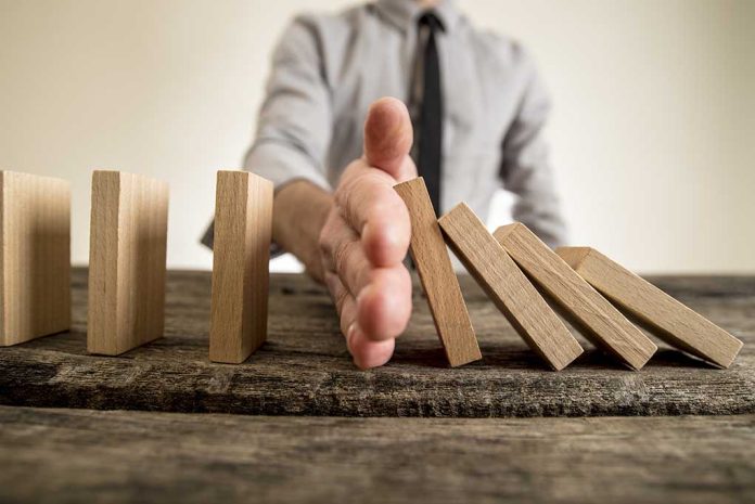 Hand stops falling dominoes on wooden table