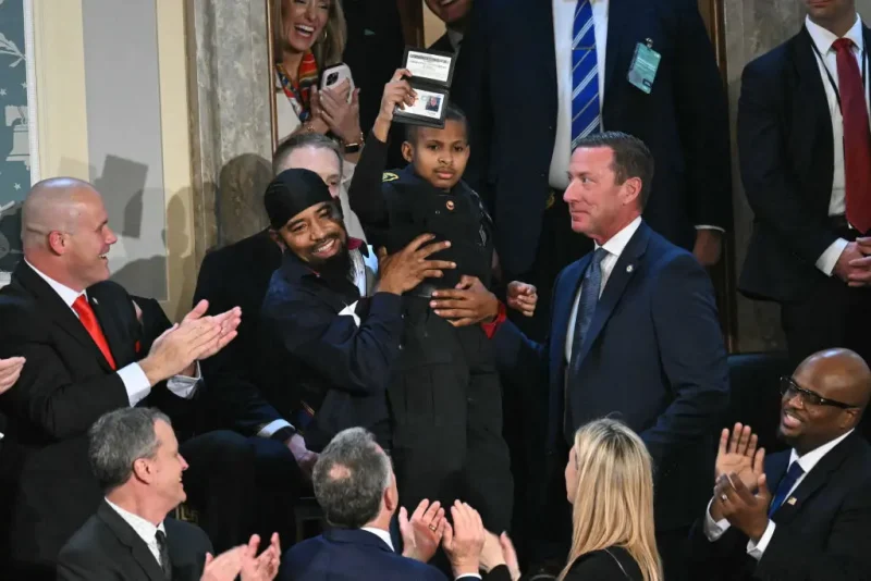 3-year-old cancer survivor Devarjaye "DJ" Daniel is lifted up by his father Theodis Daniel after given credentials from US Secret Service Director Sean Curran after US President Donald Trump made him an honorary member of the US Secret Service during his address to a joint session of Congress at the US Capitol in Washington, DC, on March 4, 2025. (Photo by SAUL LOEB / AFP) (Photo by SAUL LOEB/AFP via Getty Images)