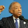 Rev. Al Sharpton in a suit speaking at the National Action Network in Harlem, holding up his fist