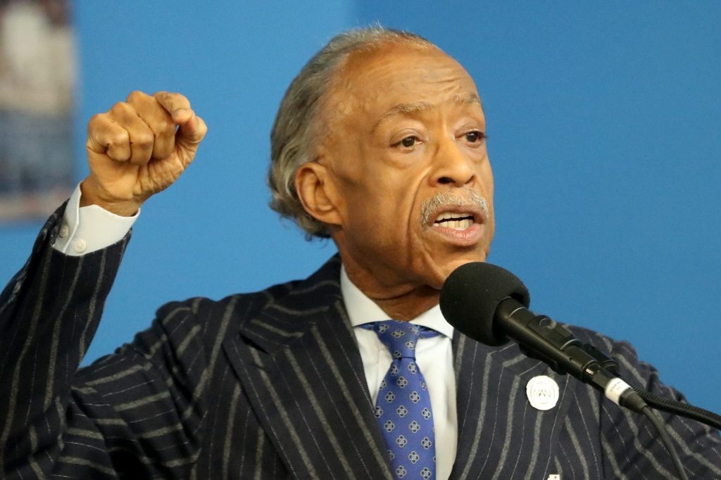 Rev. Al Sharpton in a suit speaking at the National Action Network in Harlem, holding up his fist