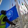 A worker prepares to hoist a United Nations flag with other national flags of participating countries at the venue of the COP28 UN climate summit in Dubai on November 30, 2023. The UN climate conference opens in Dubai on November 30 with nations under pressure to increase the urgency of action on global warming and wean off fossil fuels, amid intense scrutiny of oil-rich hosts UAE. (Photo by Giuseppe CACACE / AFP) (Photo by GIUSEPPE CACACE/AFP via Getty Images)